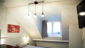 A bedroom with a bed, bedside table, lamp, window, and artwork. - Smart Appart Cherbourg La Rose des vents (Cherbourg-en-Cotentin)