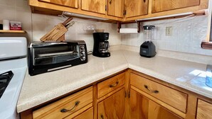 Una cocina con armarios de madera, un tostador, una cafetera y una licuadora.