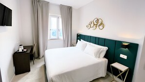 Une chambre d’hôtel moderne avec un grand lit, un bureau équipé d’une machine à café et une fenêtre avec des rideaux.