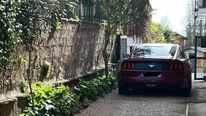 Un chemin de gravier avec une voiture rouge garée sur le bord.