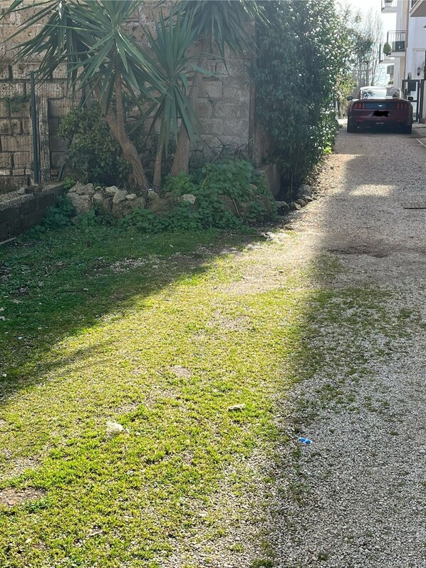 A gravel path leading to a building with a stone wall and greenery.