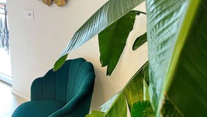 Une pièce avec un fauteuil vert, un grand miroir orné de motifs de feuilles et une grande plante.