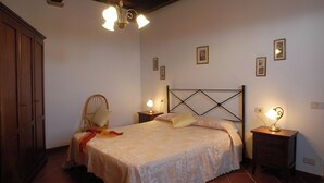 Un dormitorio con una cama, dos mesitas de noche con lámparas, un armario de madera y una silla.