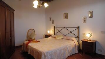 A bedroom with a bed, two bedside tables with lamps, a wooden wardrobe, and a chair.