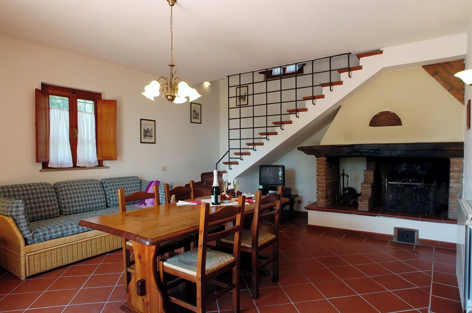 Un comedor con mesa y sillas de madera, un sofá y una escalera con chimenea.