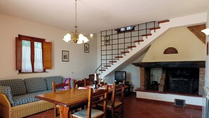 Un comedor con mesa y sillas de madera, un sofá y una escalera con chimenea.