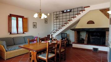 Un comedor con mesa y sillas de madera, un sofá y una escalera con chimenea.