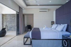 A modern hotel room with a large bed, a seating area, and a view of the outdoors. - Suluban Cliff Bali Villa (Bali)