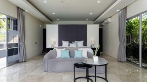A modern bedroom with a bed, bedside tables, a round table, and a large window. - Suluban Cliff Bali Villa (Bali)