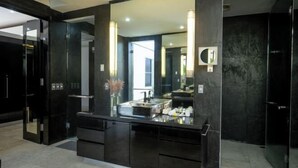 A modern bathroom with a large mirror, dark cabinetry, and a visible shower area. - Suluban Cliff Bali Villa (Bali)
