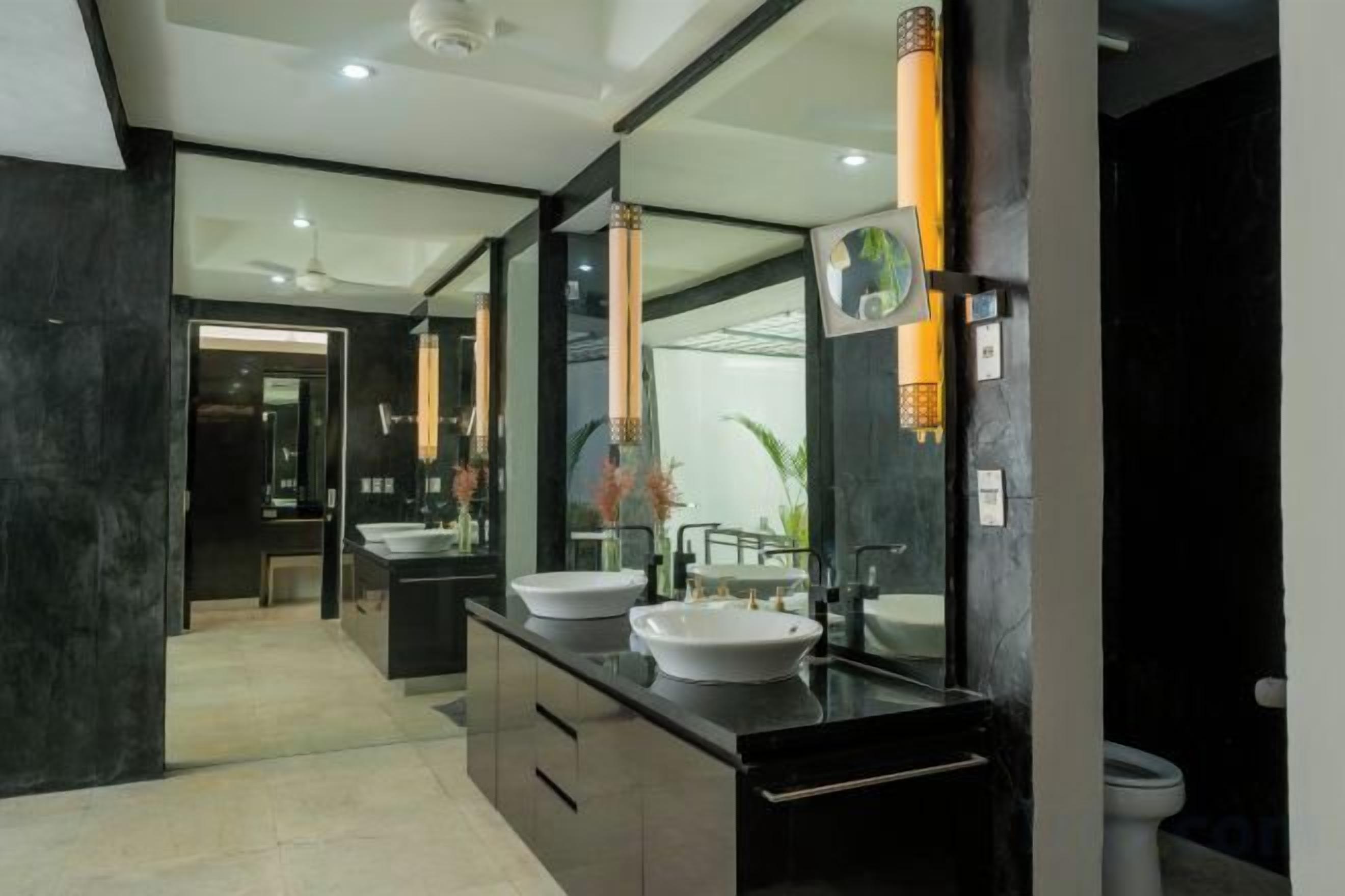 Casa de banho moderna com duas pias, um espelho grande e uma sanita.