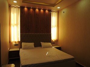 A hotel room with a large bed, two bedside tables, and wooden paneling on the wall. - Mystic Moments (Nawada)
