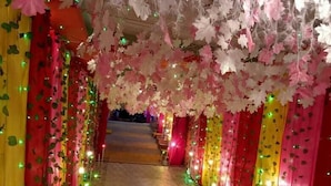A corridor with patterned flooring, red chairs, and walls adorned with hanging decorations and lights. - Mystic Moments (Nawada)
