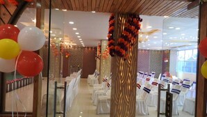 A banquet hall with white tables and chairs, a central column with floral decorations, and a sign that reads "PUSH". - Mystic Moments (Nawada)