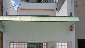 Un edificio de dos plantas con toldo verde, entrada protegida por una reja y el número '248' visible en la pared.