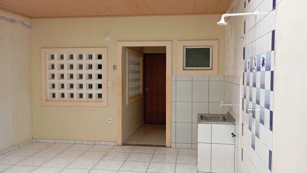 Una cocina con baldosas blancas, un lavaplatos empotrado y una ventana sobre el lavadero.