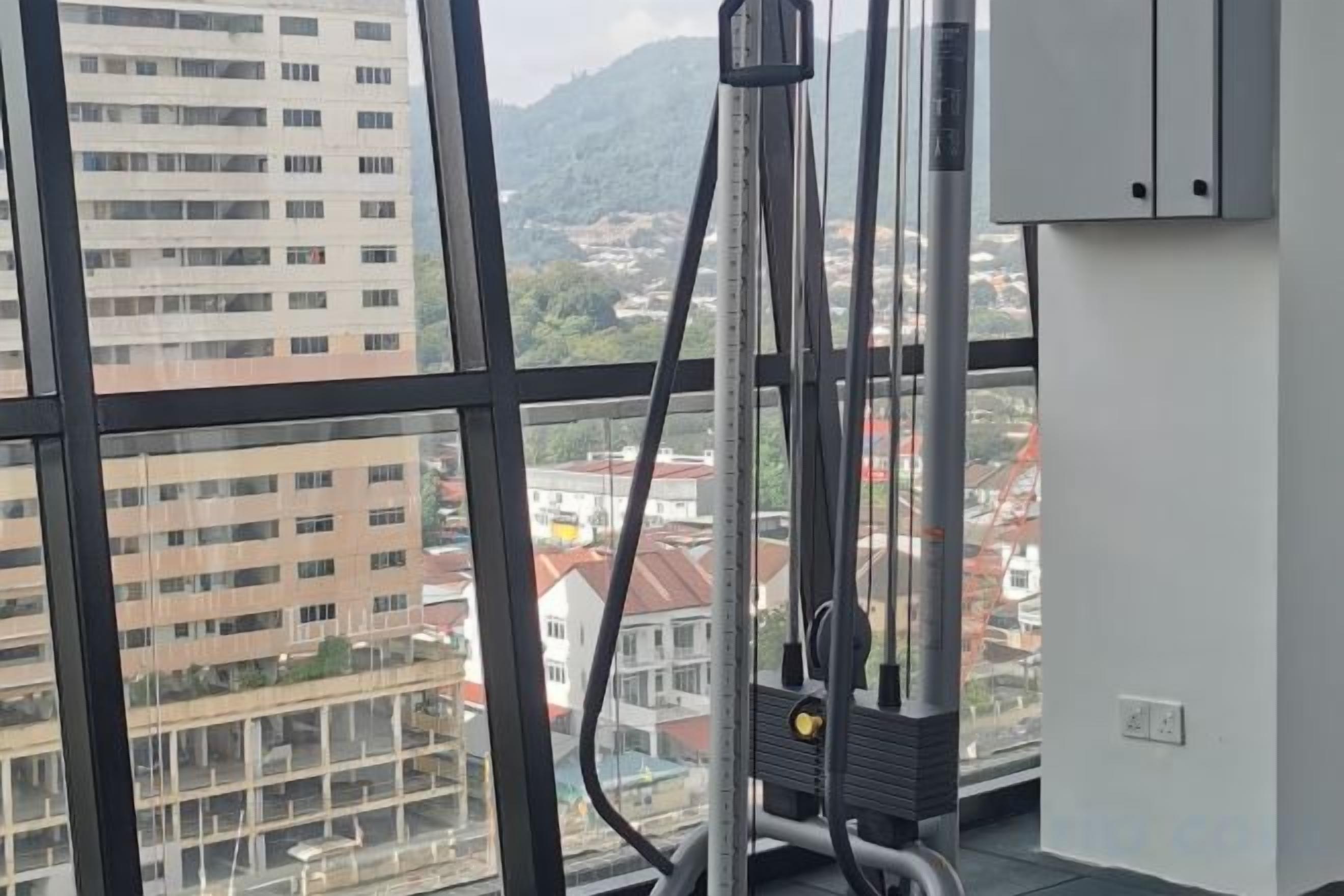 A room with a large window, a window blind, and a view of buildings and mountains.