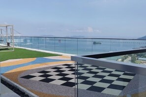 Ein Balkon mit Schachbrettboden, einer Glastrennwand und Blick aufs Meer.