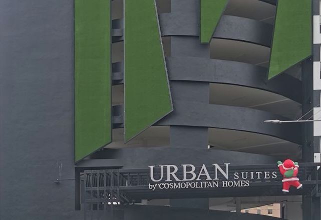 A building with a sign that reads "URBAN SUITES by 'COSMOPOLITAN HOMES' with a Santa Claus figure.
