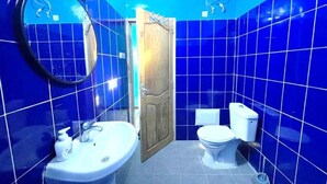 A bathroom with blue tiles, a wooden door, a sink, and a toilet. - UBANGUI residence. A unique, calm and inspiring setting! Suitable for creation! (Gandon, Saint-Louis)