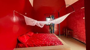 A room with a bed under a white canopy, red walls, and a small table. - UBANGUI residence. A unique, calm and inspiring setting! Suitable for creation! (Gandon, Saint-Louis)