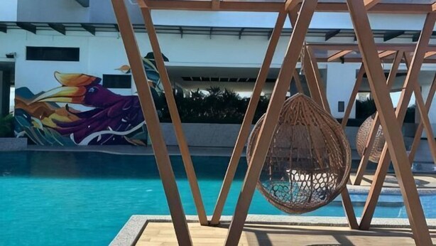 Un área de piscina con una silla colgante y un mural.