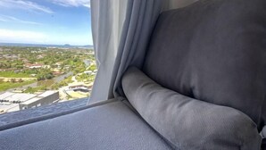 Asiento junto a la ventana con vistas al paisaje, cortinas y un cojín.