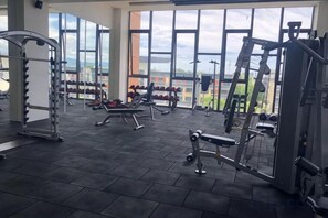 A gym with various exercise equipment, large windows, and a view of the outside. - K Avenue Sunset Seaview, KK Airport View - Free Parking (Donggongon)