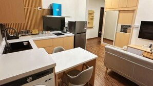 Cocina compacta con lavamanos, estufa y refrigerador, un pequeño comedor con mesa y sillas, y un sofá.