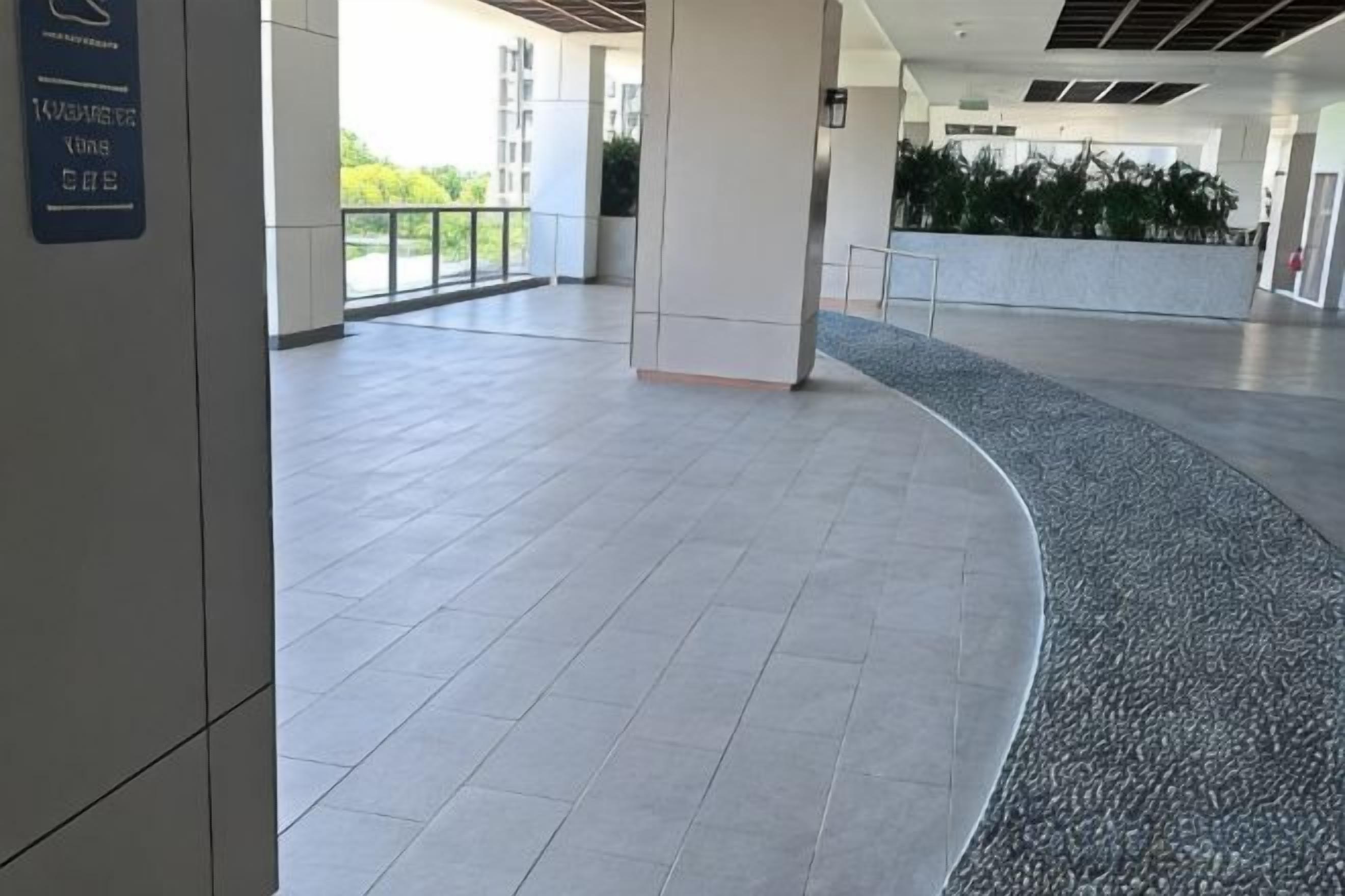 Tilava sisätila, jossa on kaareva lattia, seinässä kyltti ja näkymä vihreälle alueelle ulos.