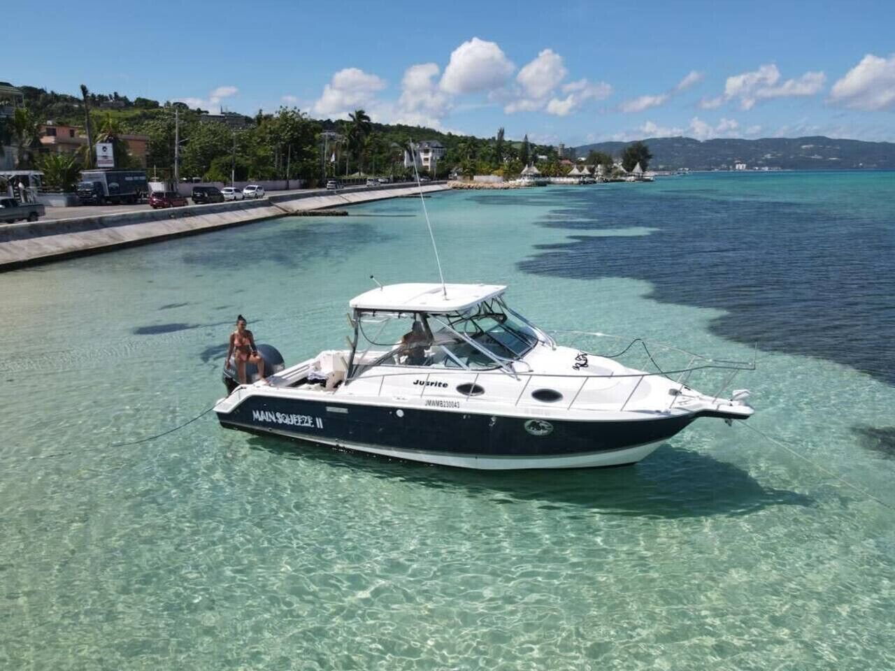 A boat named 'MAIN SHIP 2' docked at a marina with clear turquoise water.