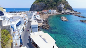 Une ville côtière aux bâtiments blancs, dotée d’une plage rocheuse et bordée d’eaux d’un bleu limpide.