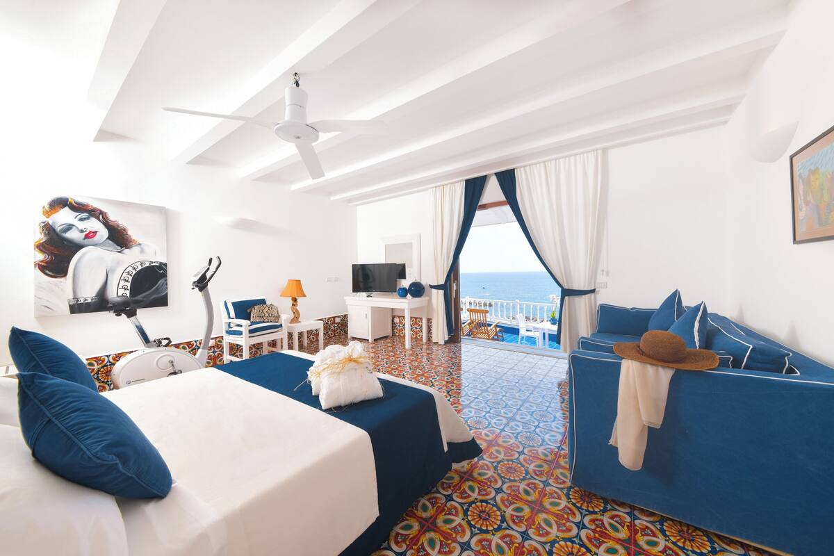 Une chambre d’hôtel avec un lit, un bureau, une télévision et un canapé.