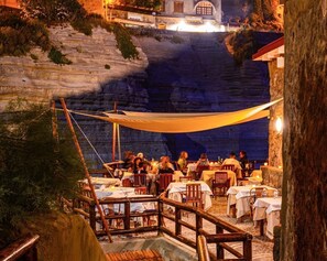 An outdoor dining area with tables and chairs, overlooking a cliffside.
