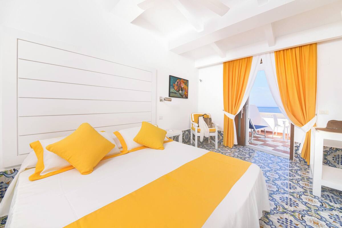 Une chambre d’hôtel avec un lit, un bureau et une vue sur la mer.