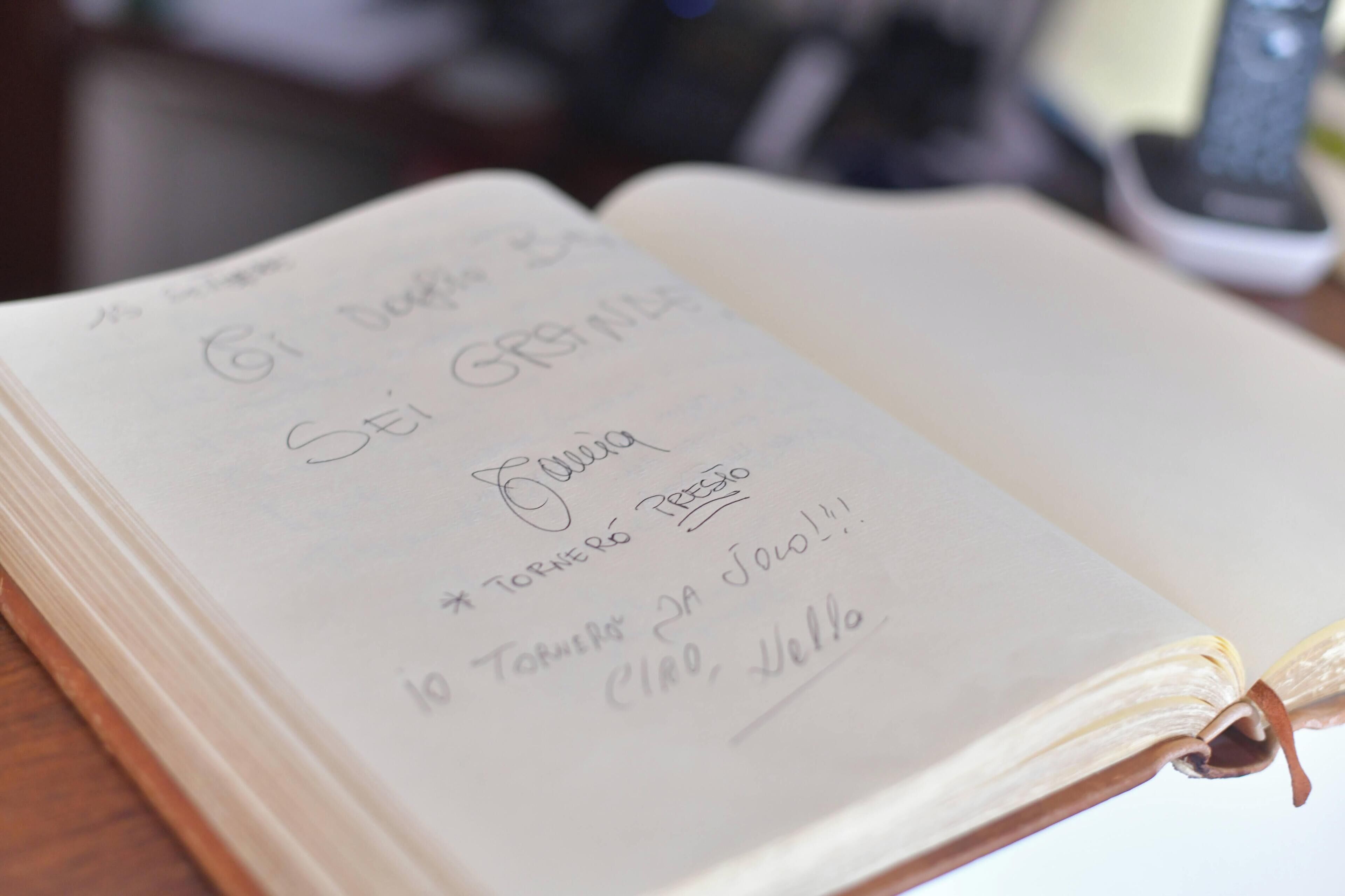 An open notebook with handwritten text on a wooden surface.