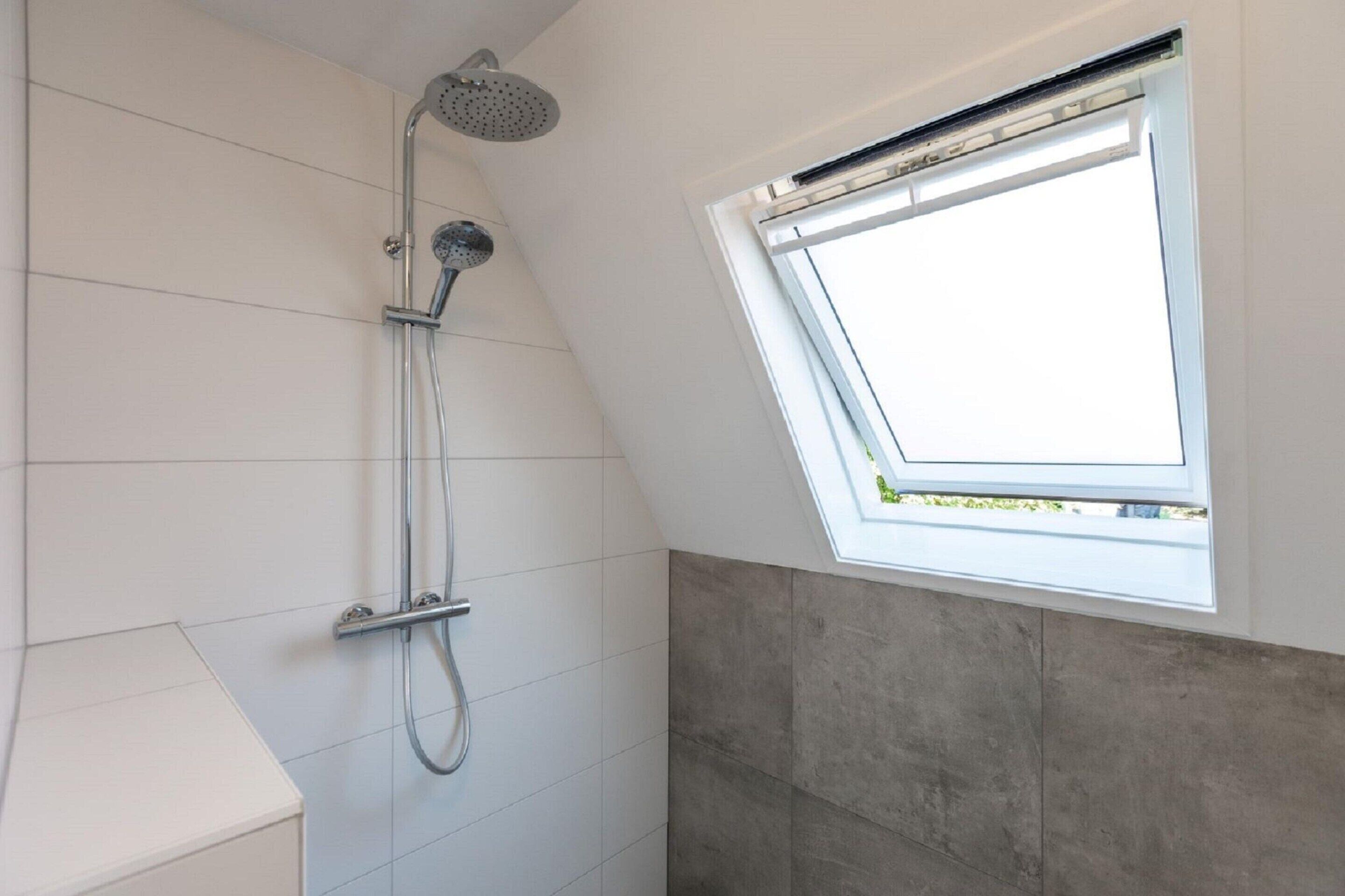 A modern bathroom with a skylight, a shower, and a white sink.