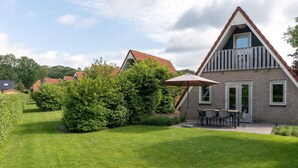 A modern house with a triangular roof, a balcony, and a well-maintained lawn. - Holiday Home in Plasmolen Near Nature Reserves (Plasmolen)