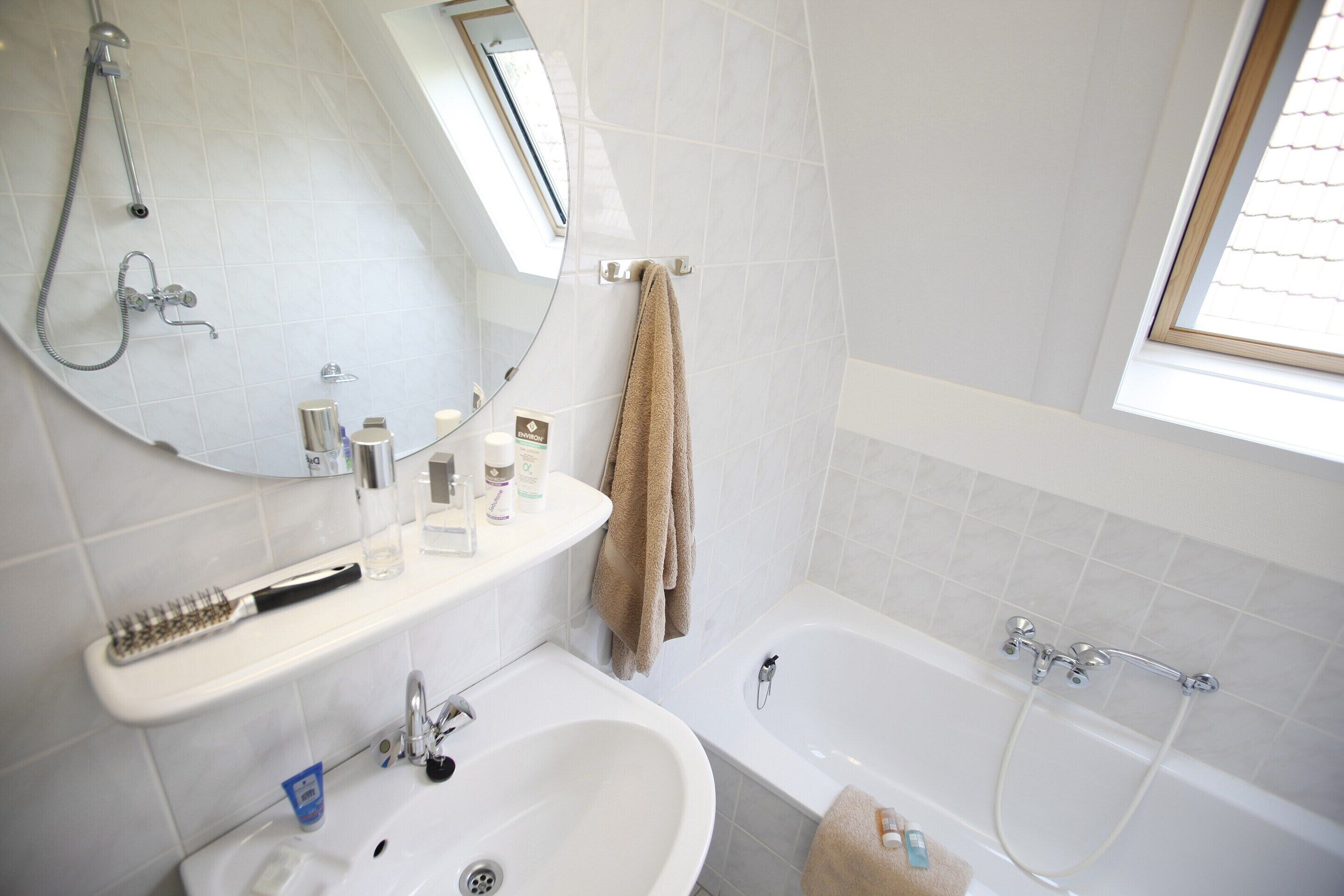 Un baño moderno con bañera, lavamanos, espejo y perchero.