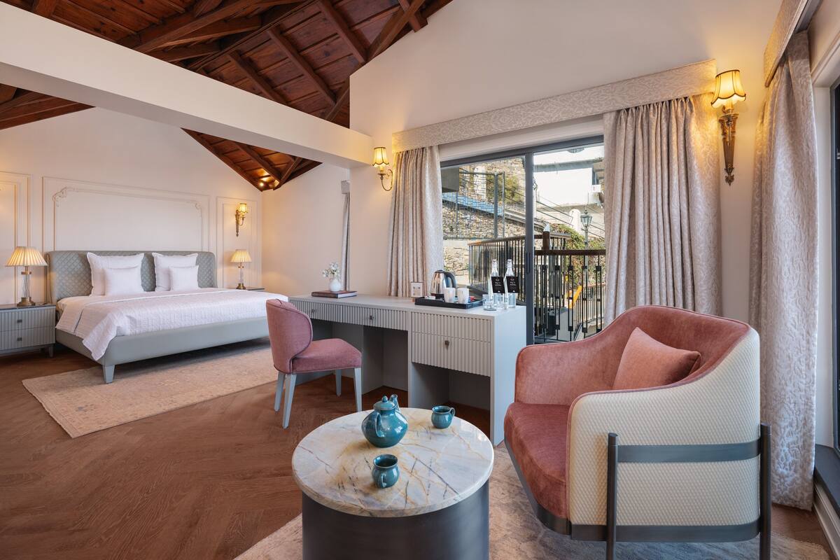 Un dormitorio con cama, escritorio, silla y vistas al exterior.