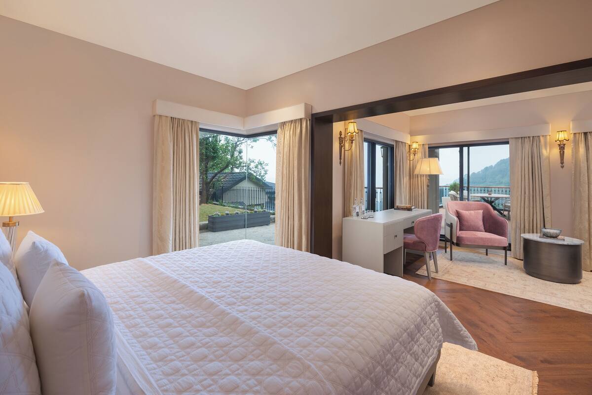 Habitación de hotel con una cama grande, un escritorio, una silla y vistas al exterior.