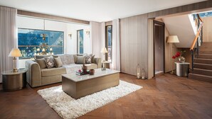 Una sala de estar moderna con un sofá, una mesita de centro y una lámpara. Se ve una escalera que conduce a un nivel superior.