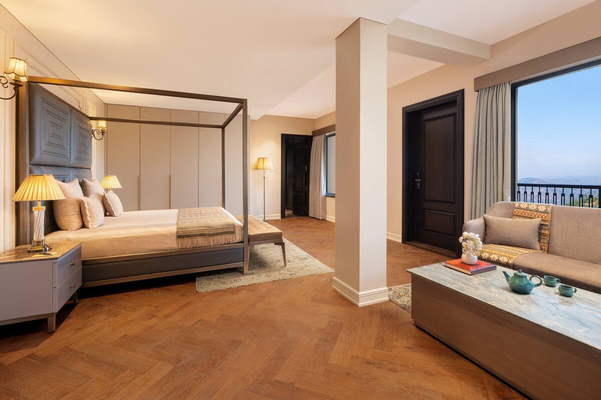 Un dormitorio espacioso con cama con dosel, una zona de estar con sofá y vistas a la ciudad.