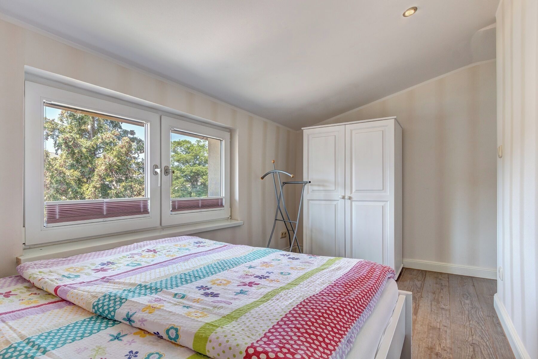 Une chambre à coucher avec un lit, une armoire et une fenêtre équipée de stores.