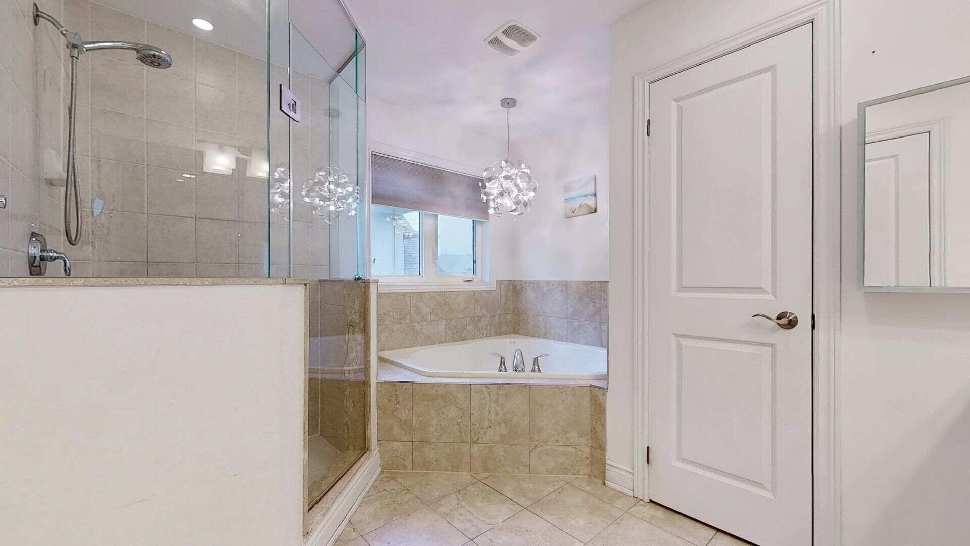 A modern bathroom with a glass shower enclosure, a freestanding bathtub, and a white door.