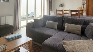 Una sala de estar con un sofá, una mesa y un ventanal con cortinas.