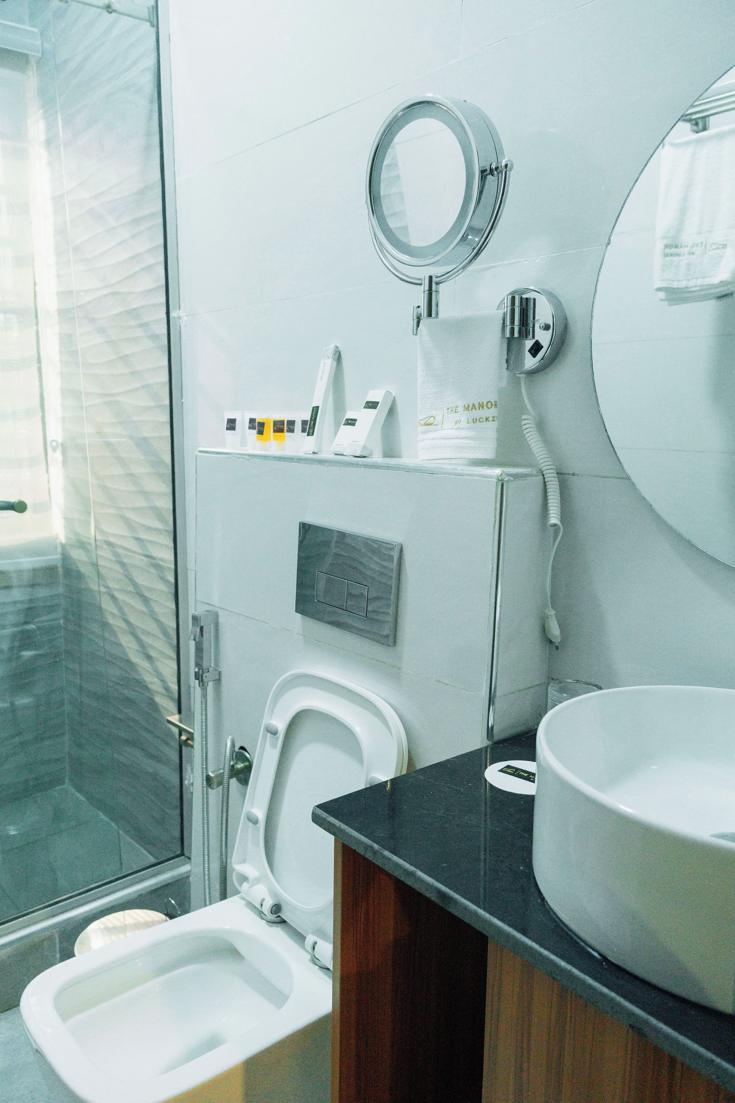 A modern bathroom with a glass shower enclosure, a toilet, a sink, and a mirror.