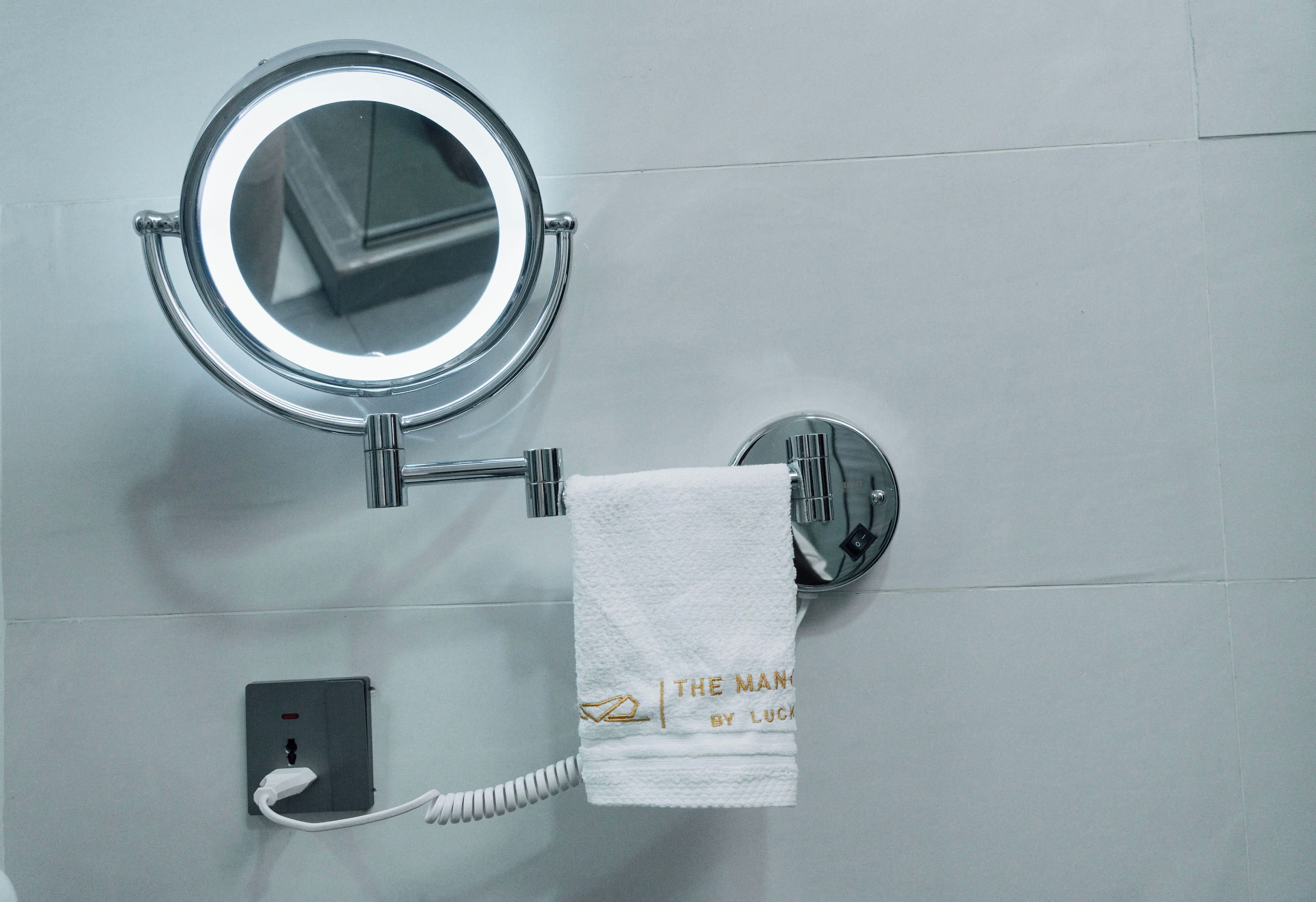 A bathroom with a round mirror, a towel rack with a white towel, and a telephone.