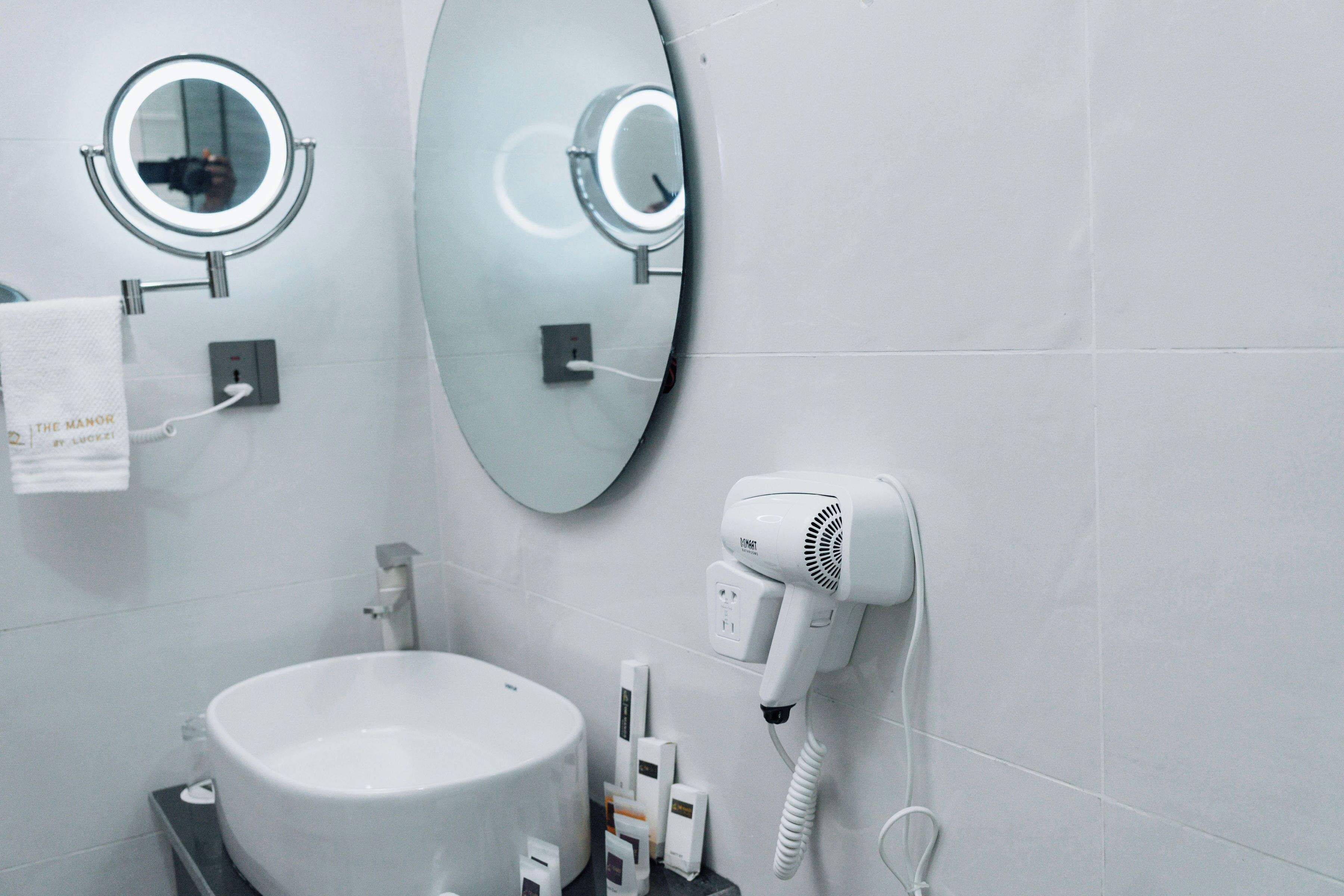 Une salle de bain équipée d’un lavabo, d’un miroir et d’un sèche-cheveux.