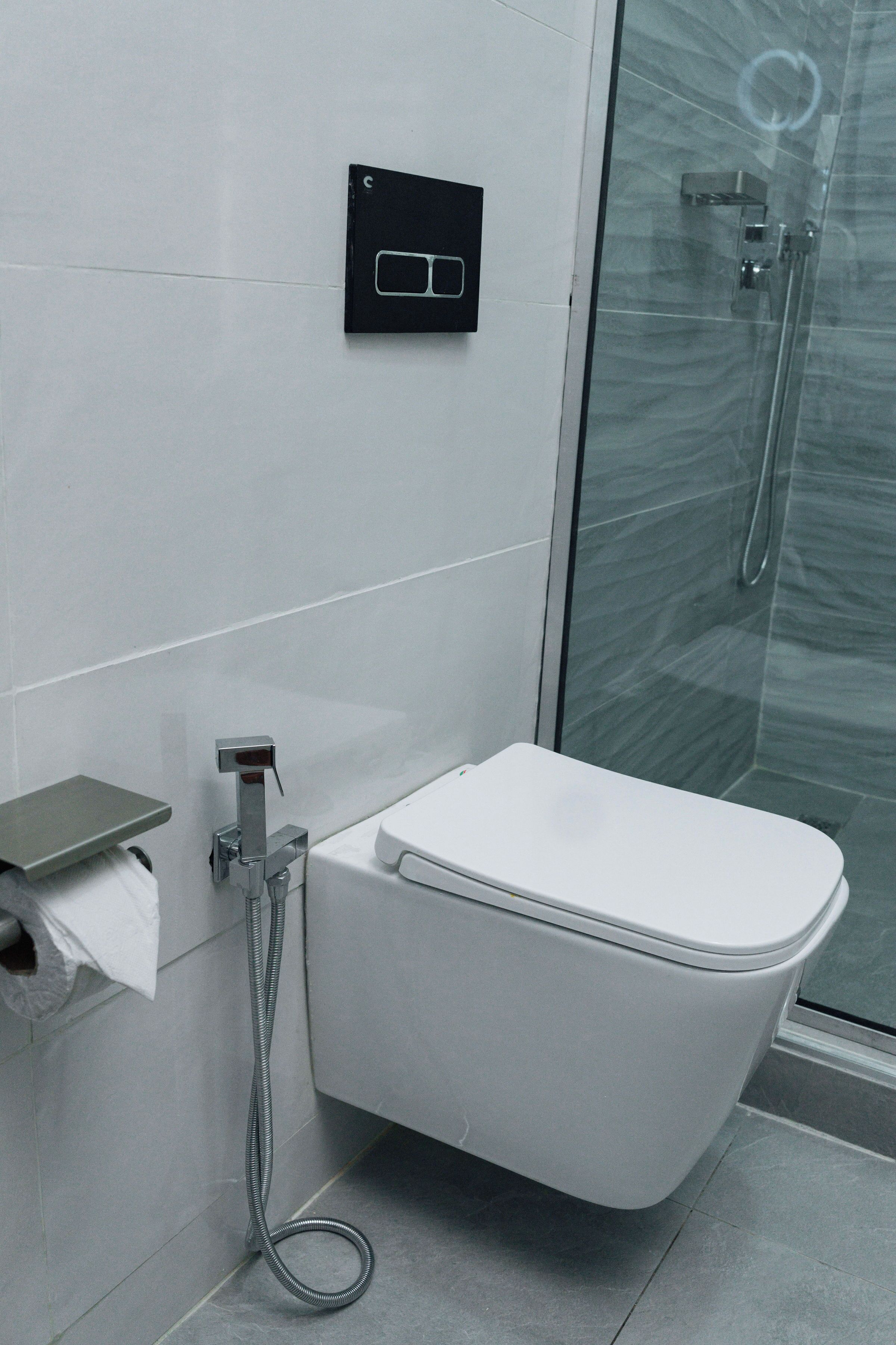 A modern bathroom with a toilet, a glass shower enclosure, and a towel rack.